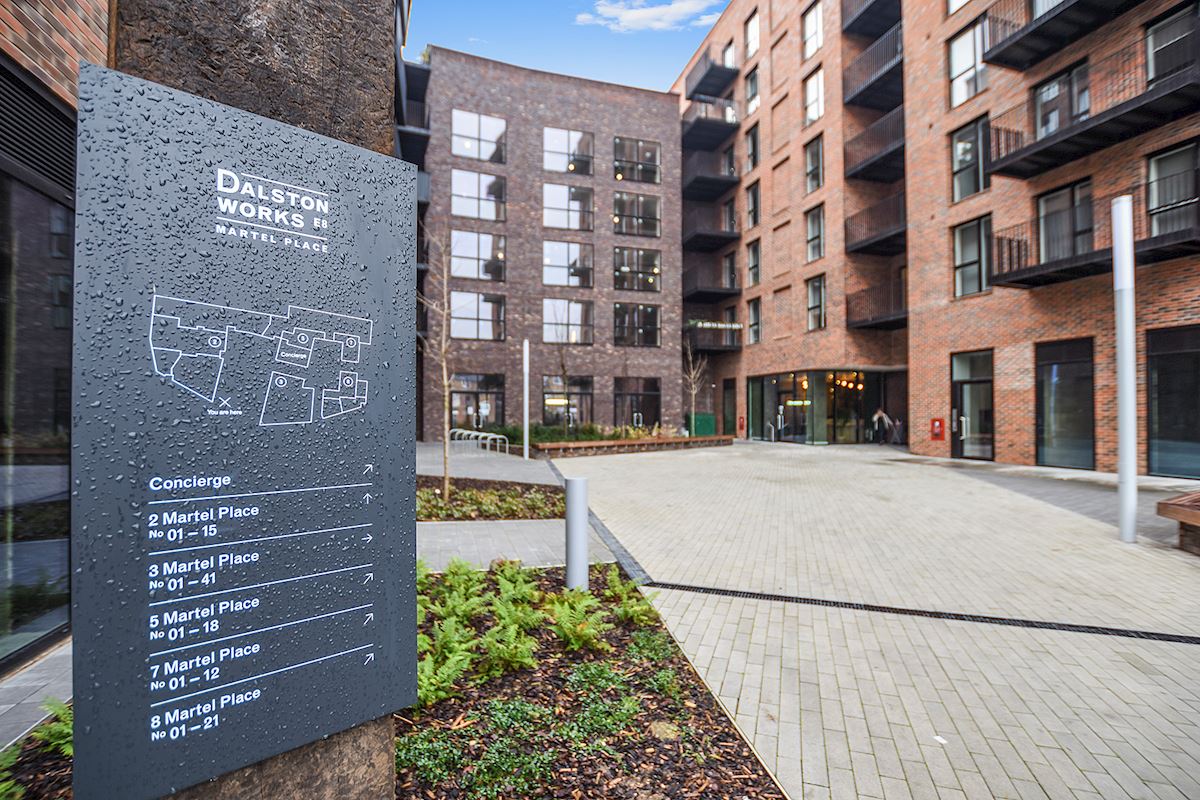 Arrival at Dalston Works from Martel Place, with the wayfinding marker and brick residential buildings surrounding the courtyard